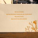 Photo of a postcard with orange text and a flower on the bottom right.
