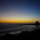  Infamous Martins Beach, its oft-photographed rock jutting out of the ocean as the sun's last rays illuminate the moon in the left-hand corner, the ripple of waves in the rainbow reflection crashing on the darkened sand.