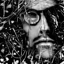 A black & White self-portrait scanograph. My face is looking directly at the viewer. I am wearing thick black framed magnifying glasses. There is debris and detritus floating over my face and throughout the frame. These obstructions represent the floaters I experience in my own vision. This image is from my “Blind Vision” series. 