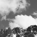 Black and white photo of a cloudy sky with mountains on the bottom of the image. 