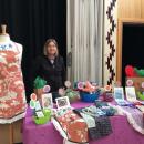 Image of Cicely standing in front of her work at a table