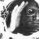 This is one of my most iconic images from my “Blind Vision” series. It is a Black & white scanographic self-portrait. The frame is filled with white foam. My face appears through a darkness at the right side of the frame. There is a monocular in my eye and streaks of white foam across my face. 