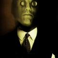 A scanograph, photomontage color self- portrait depicting me with a lizard’s face with magnifying lenses over my eyes. I am wearing a business suit and tie. This image is from my “Transmog Project” body of work.