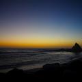  Infamous Martins Beach, its oft-photographed rock jutting out of the ocean as the sun's last rays illuminate the moon in the left-hand corner, the ripple of waves in the rainbow reflection crashing on the darkened sand.