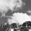 Black and white photo of a cloudy sky with mountains on the bottom of the image. 