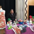 Image of Cicely standing in front of her work at a table