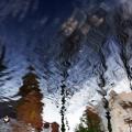 Photograph that is a clear water ripple with a reflection of a town. 